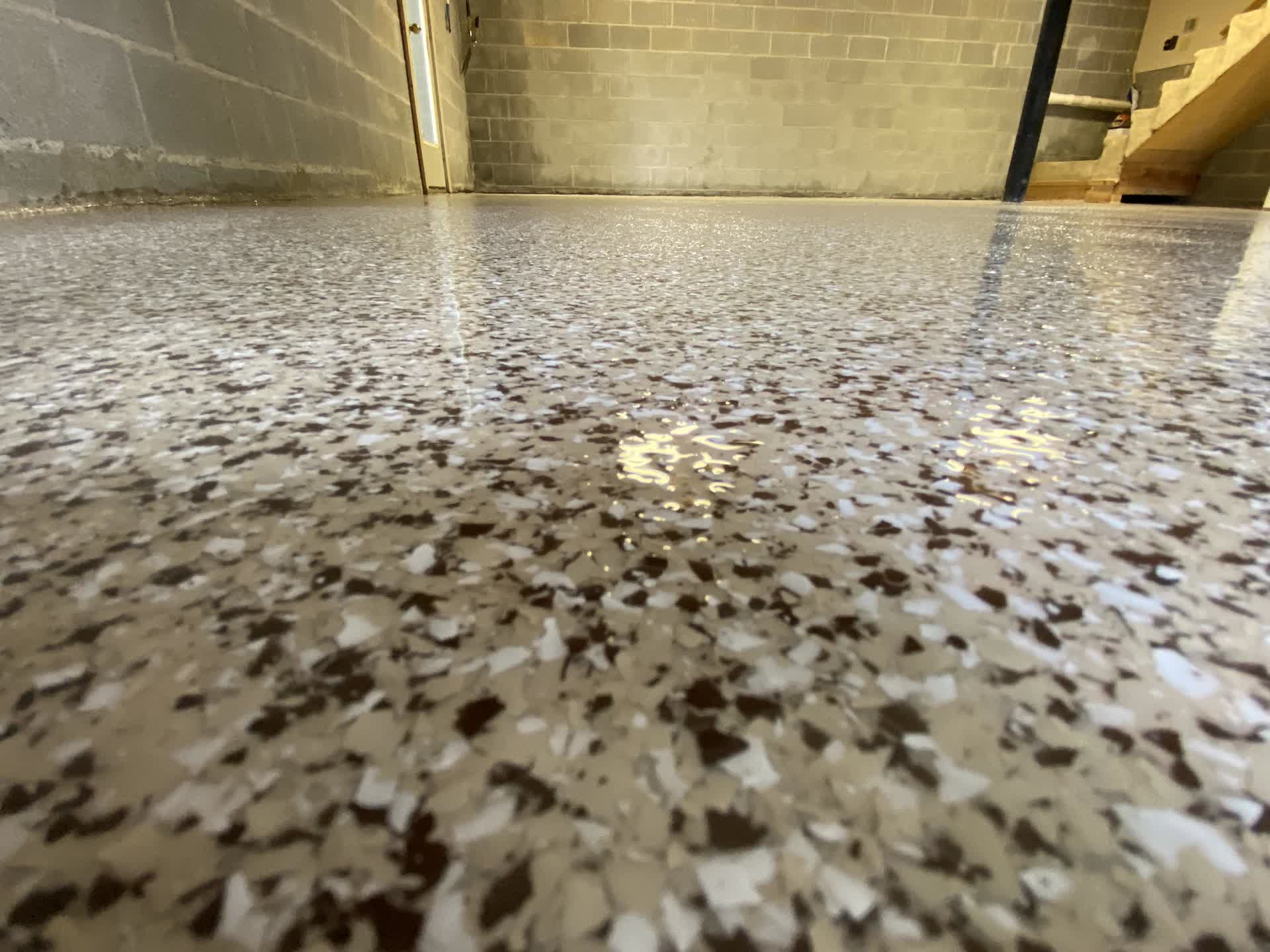 Brown and cream flake floor in a block-walled basement with stairs at the back in Mississippi