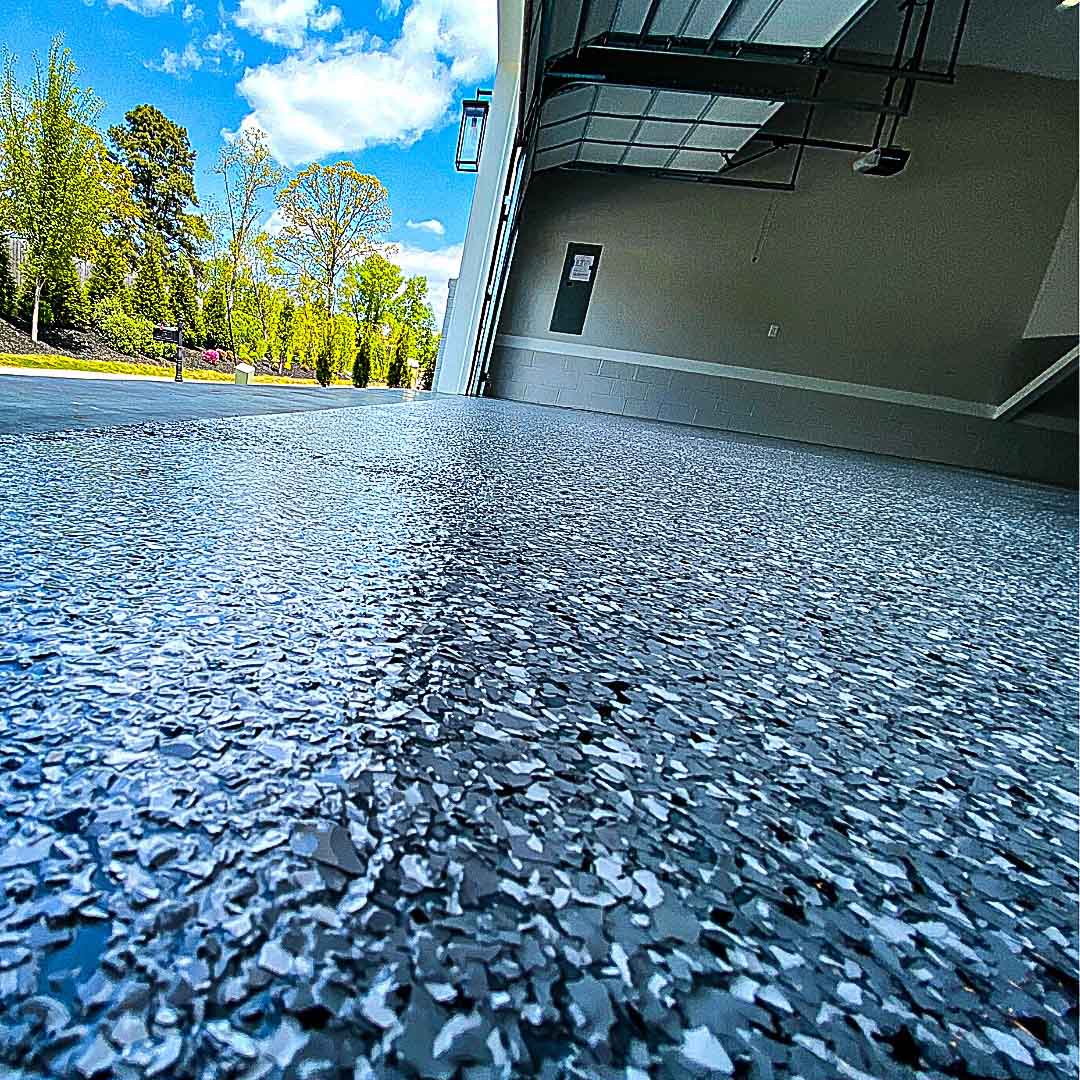 Blue-gray flake coating running from a garage out onto the driveway apron under a clear sky in Laurel, Mississippi