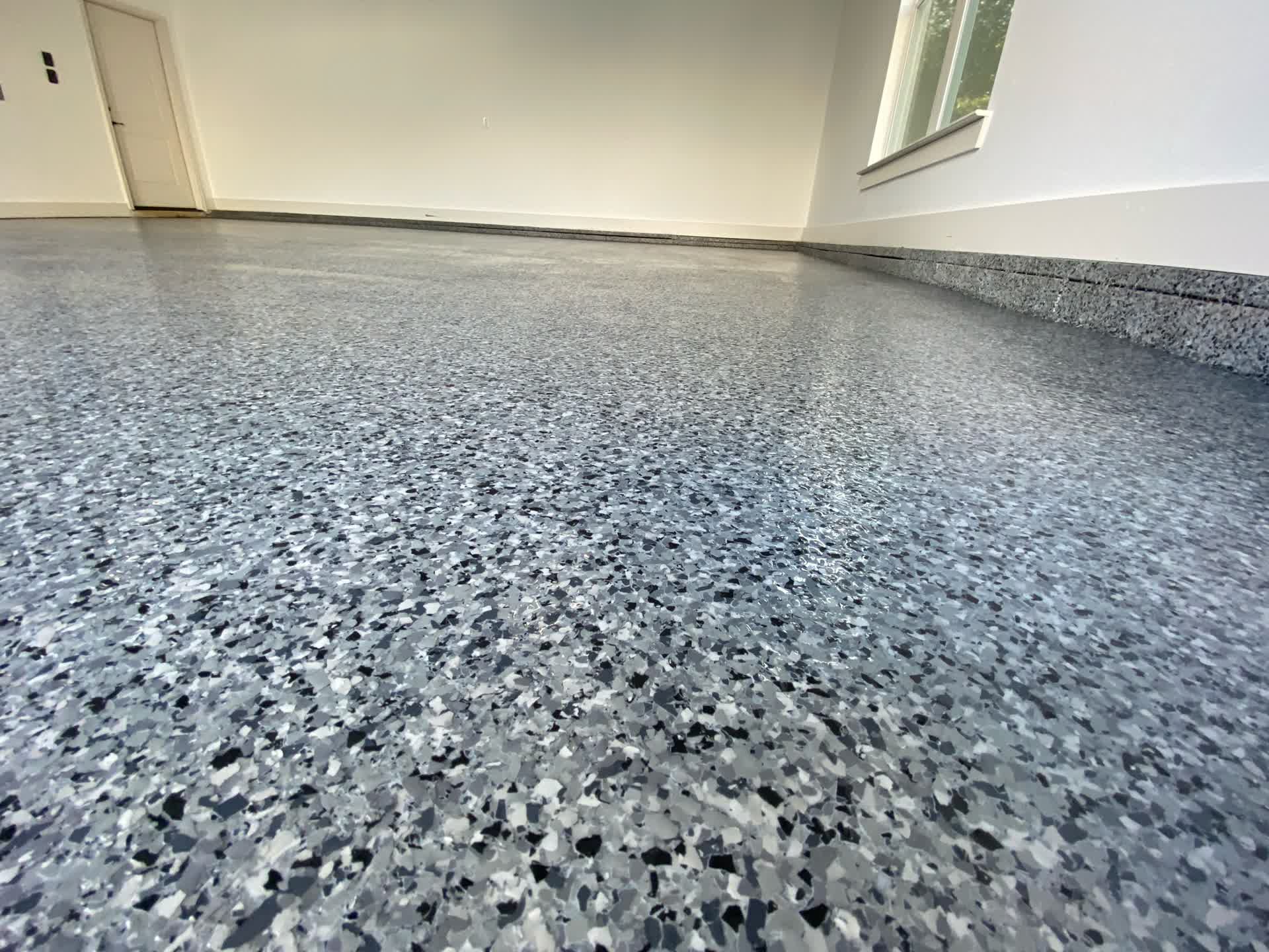 Blue-grey flake garage floor in an empty finished garage with a coved base along the wall