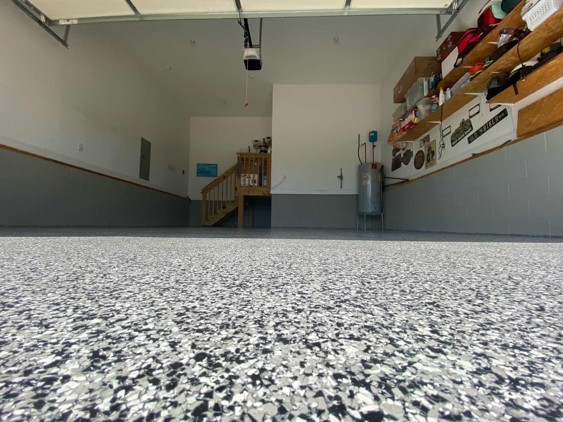 Black and white flake garage floor with shelving, a water heater and stairs to the house in Mississippi