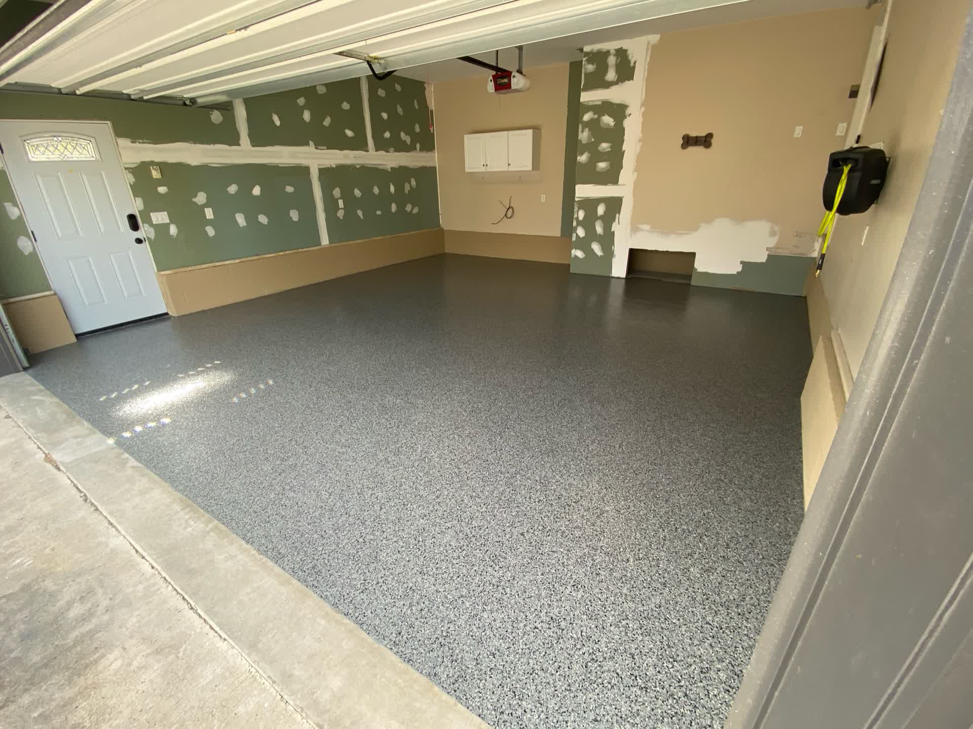 Grey flake garage floor viewed from outside with the door up and green and tan walls