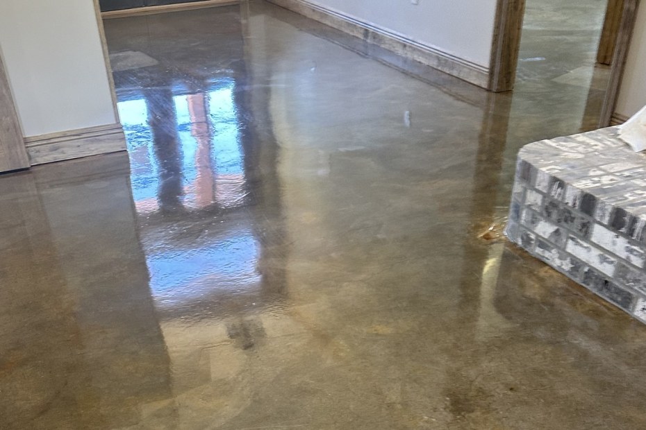 Stained and polished concrete floor with a high gloss, reflecting a doorway in a house under construction